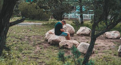 Poika istuu kivellä metsässä