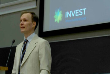 Vili Lehdonvirta puhujanpöntössä, takanaan INVESTin logo.