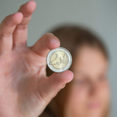 Nuori näyttää 2 euron kolikkoa.