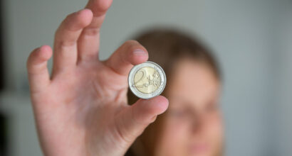 Nuori näyttää 2 euron kolikkoa.