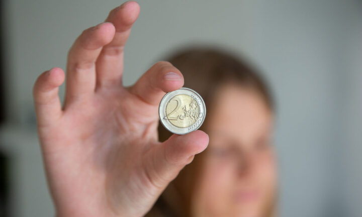 Nuori näyttää 2 euron kolikkoa.