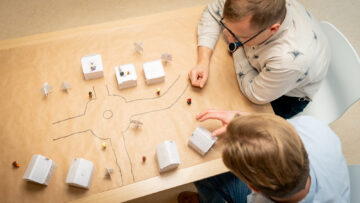 Tunnistamattomat tutkijat tutkivat kaupungin pienoismallia.