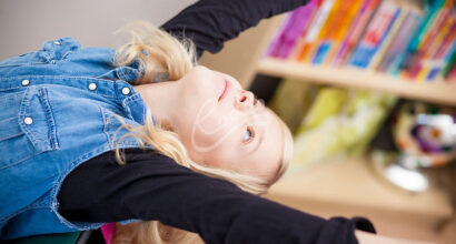 Nuori venyttelee kirjahyllyn edessä.