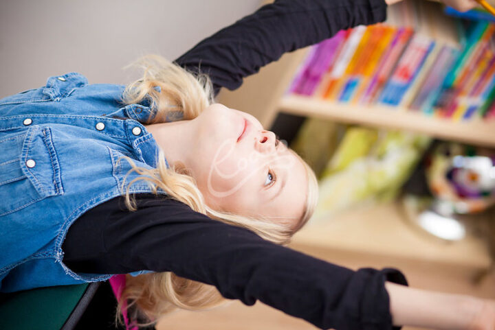 Nuori venyttelee kirjahyllyn edessä.