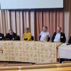 Ihmisiä rivissä paneelikeskustelussa.