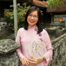 A vietnamese woman standing next to a stone wall