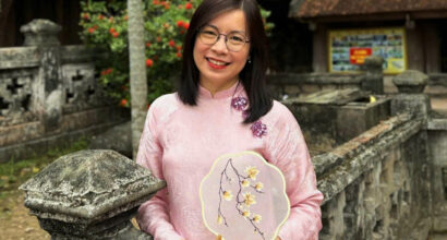 A vietnamese woman standing next to a stone wall