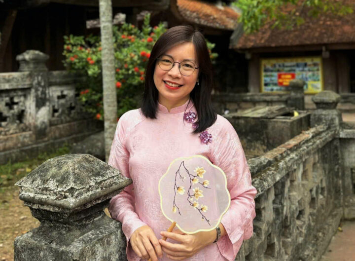 A vietnamese woman standing next to a stone wall