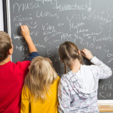 Koululaiset kirjoittavat liitutaululle.