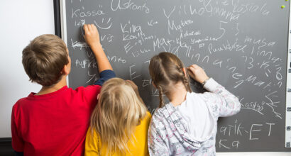Koululaiset kirjoittavat liitutaululle.